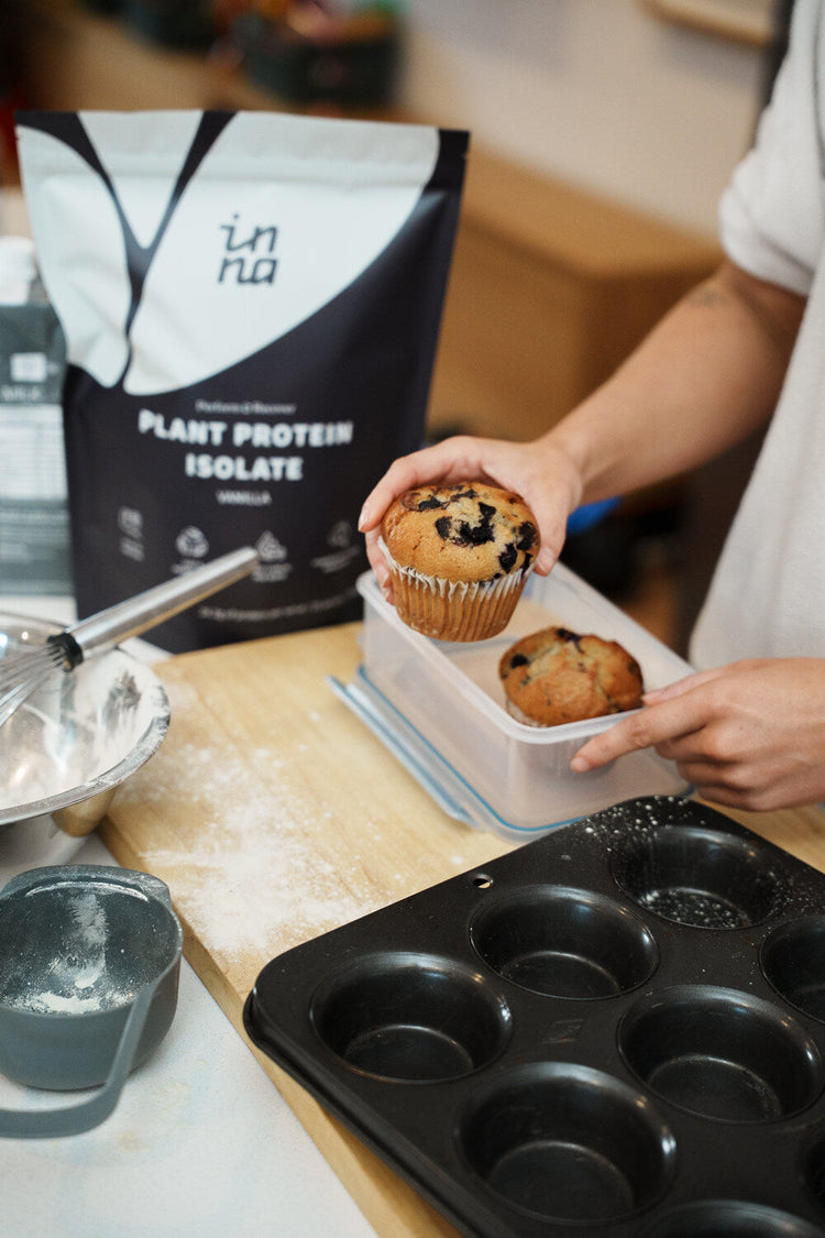 A person holding a cupcake next to a bag of the Inna Protein Vanilla flvour