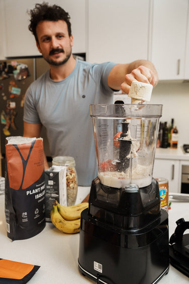 A man tipping a scoop of Inna protein powder into a blender