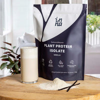 Inna Protein plant protein isolate package with a glass of vanilla protein shake on a wooden surface.