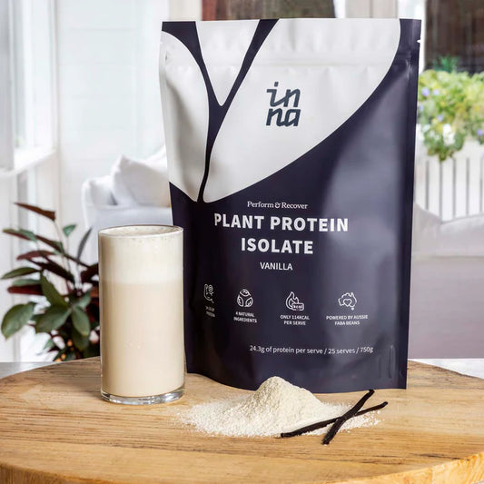 Inna Protein plant protein isolate package with a glass of vanilla protein shake on a wooden surface.
