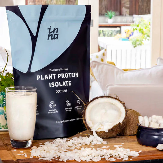 Inna Protein coconut plant protein isolate package with a glass of protein shake and coconuts on a table.